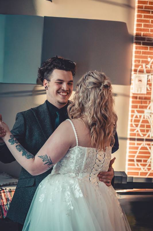 Groom smiling at his bride in a brick hall